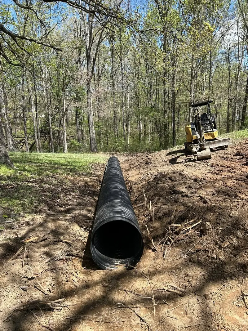 Culvert pipe being installed in a ditch with a mini excavator