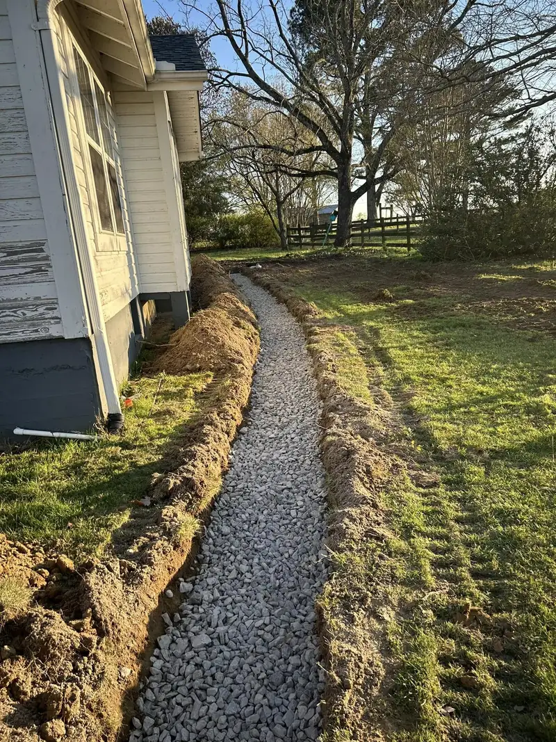 Gravel French drain running along the side of a house