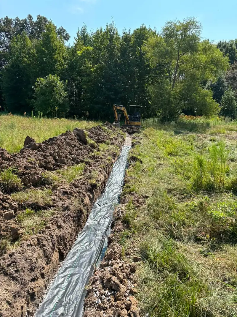 Perforated pipe in a fabric-lined French drain trench
