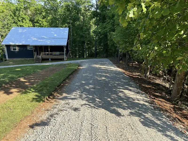 Finished gravel driveway leading to a cabin in the woods