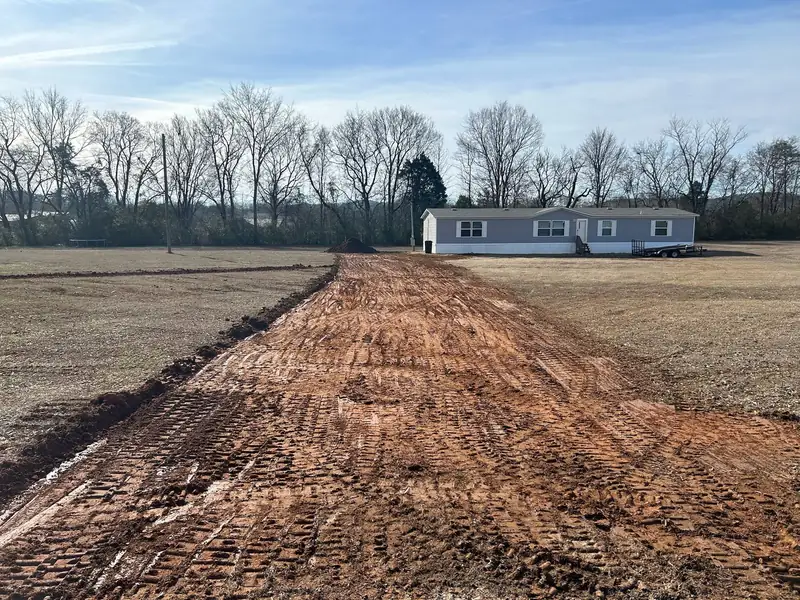 Driveway cut and graded in red clay before gravel