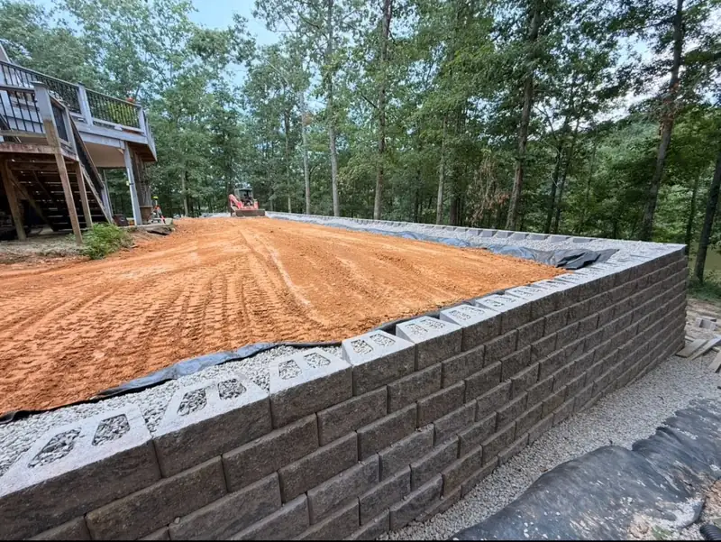 Block retaining wall with a graded pad above it