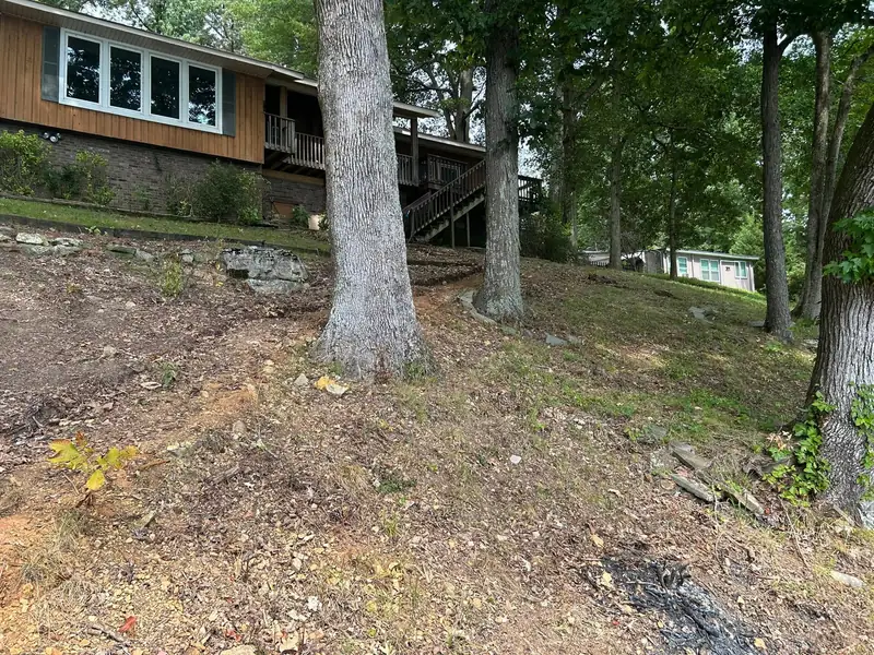 Steep, worn slope behind a lake house before the work