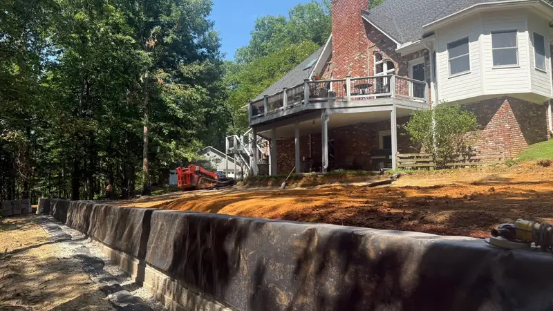 Retaining wall being backfilled behind a lake house